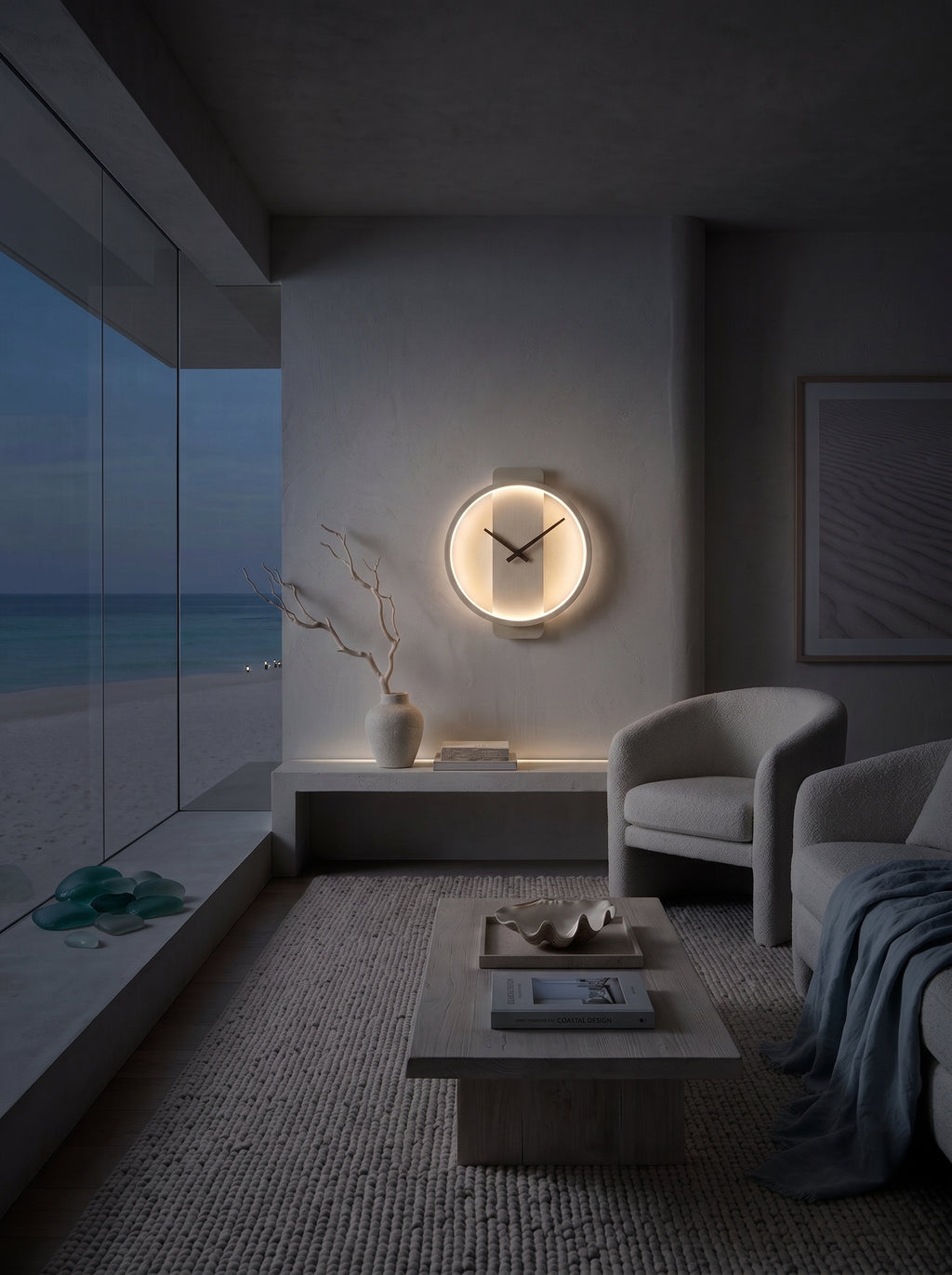 A modern minimalist living room at dusk with a glowing circular wall clock mounted above a low shelf. The room features a beige armchair, a low wooden coffee table, a textured rug, and a large floor-to-ceiling window overlooking a beach at twilight.