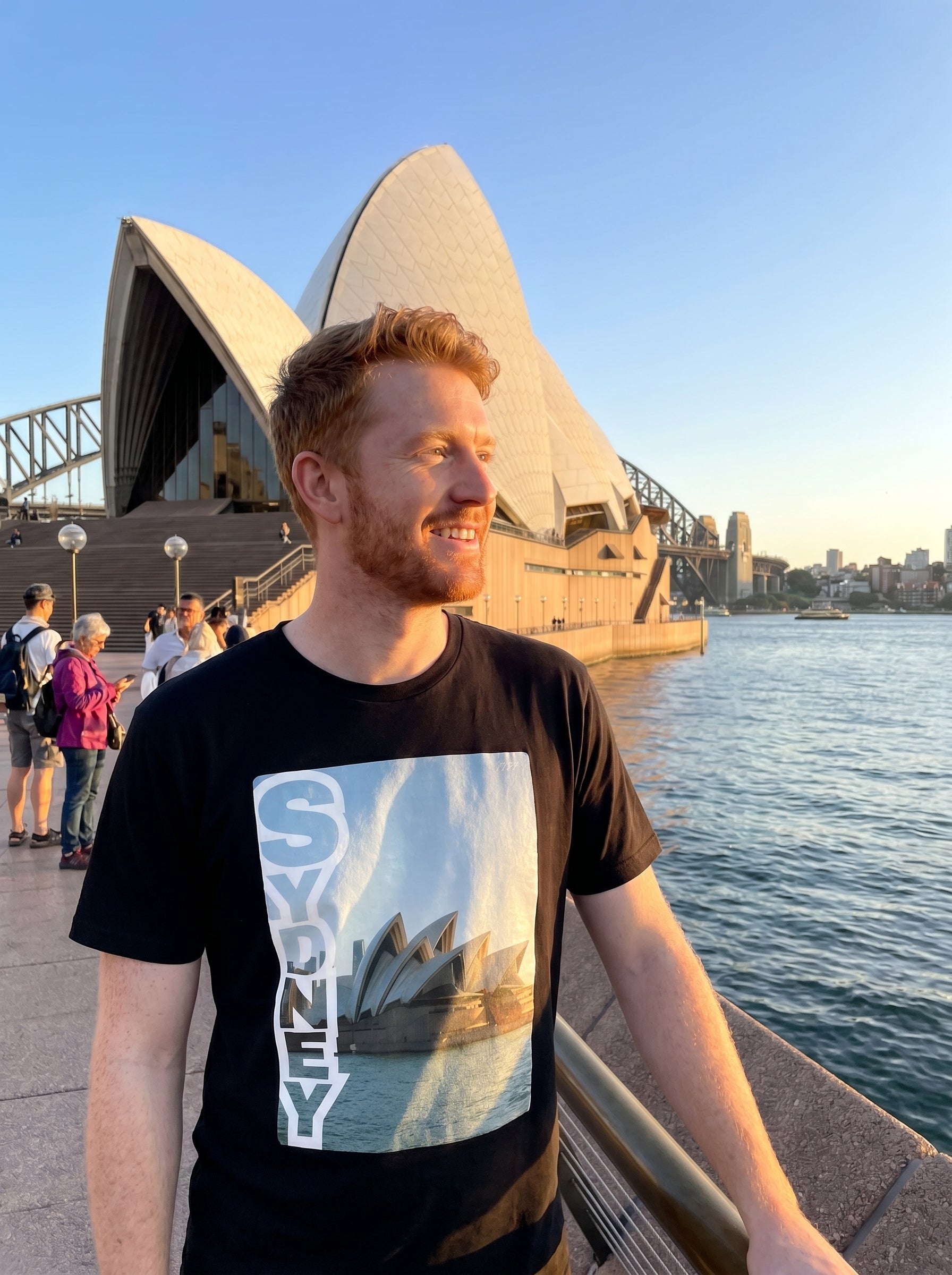 Person wearing a t-shirt with a Sydney Harbour Bridge design in front of the Sydney Opera House.