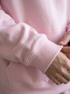 Close-up of a person wearing a pink hoodie with a focus on the sleeve and hand.