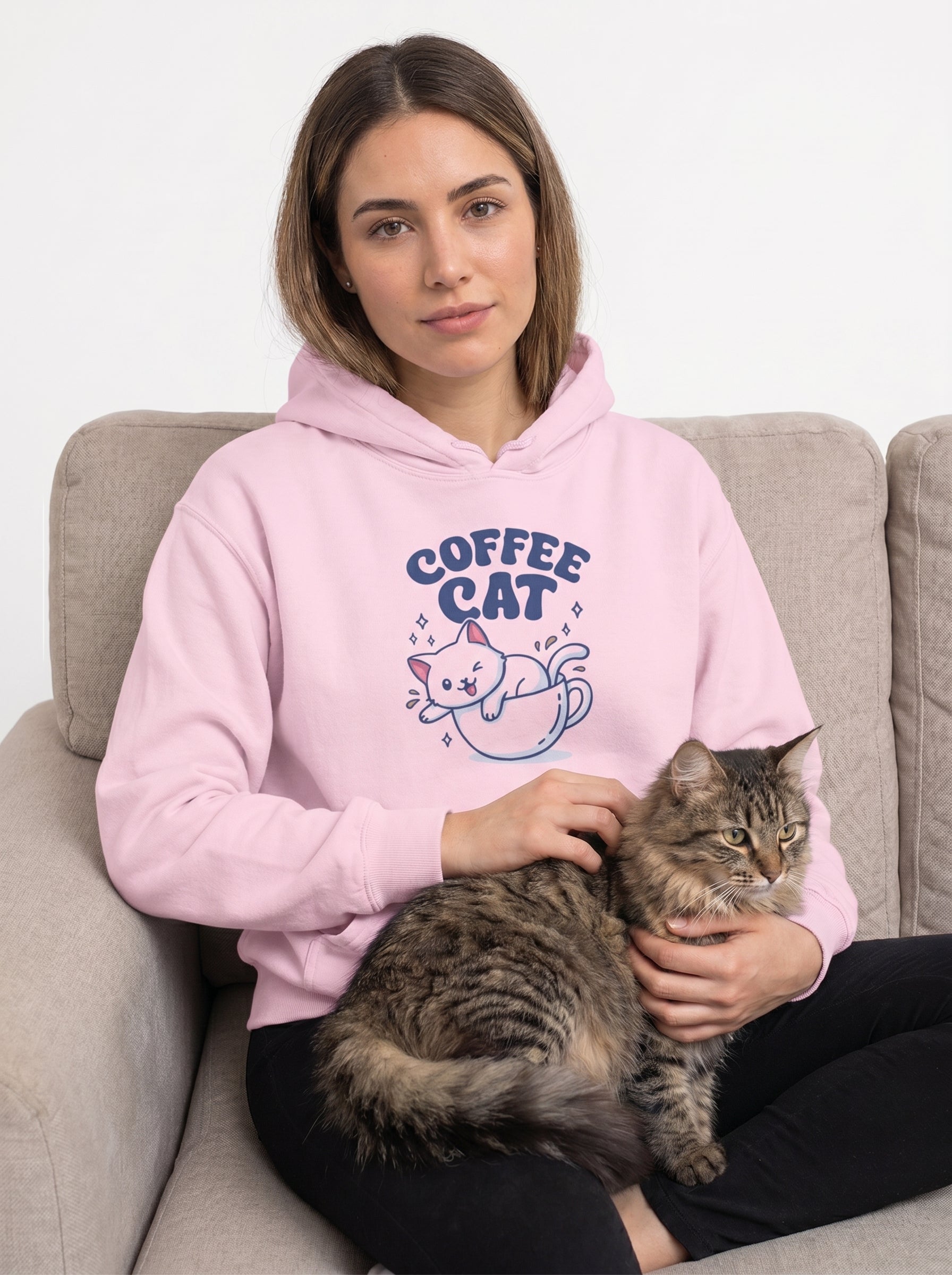 Woman wearing a pink 'Coffee Cat' hoodie sitting on a couch with a cat.