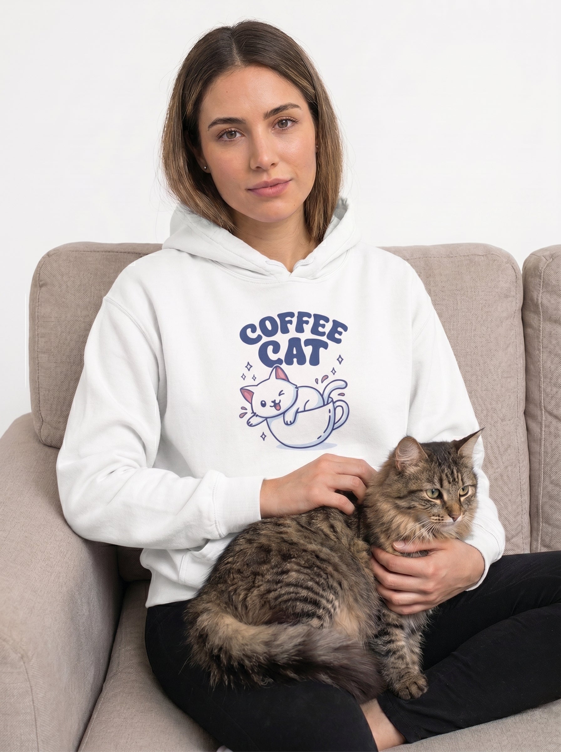 Woman wearing a hoodie with 'Coffee Cat' design, sitting on a couch with a cat.