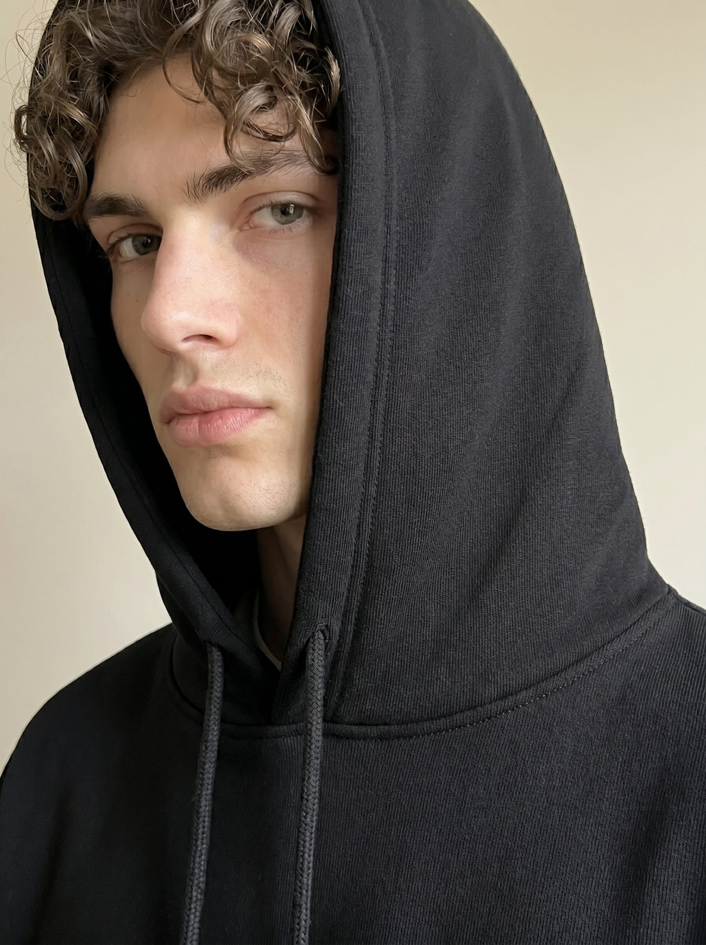 Person wearing a black hoodie with a neutral background