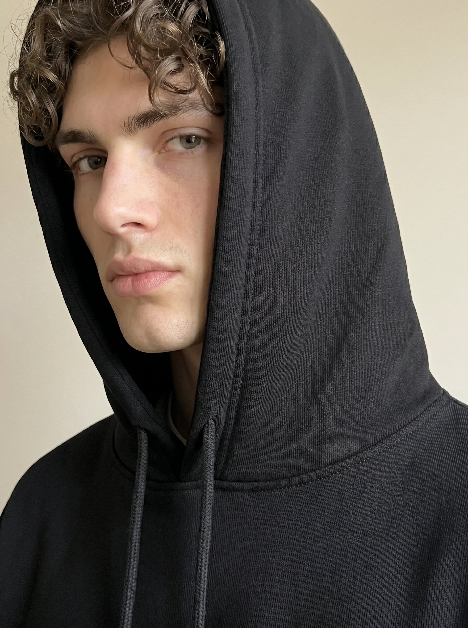 Person wearing a black hoodie with a neutral background