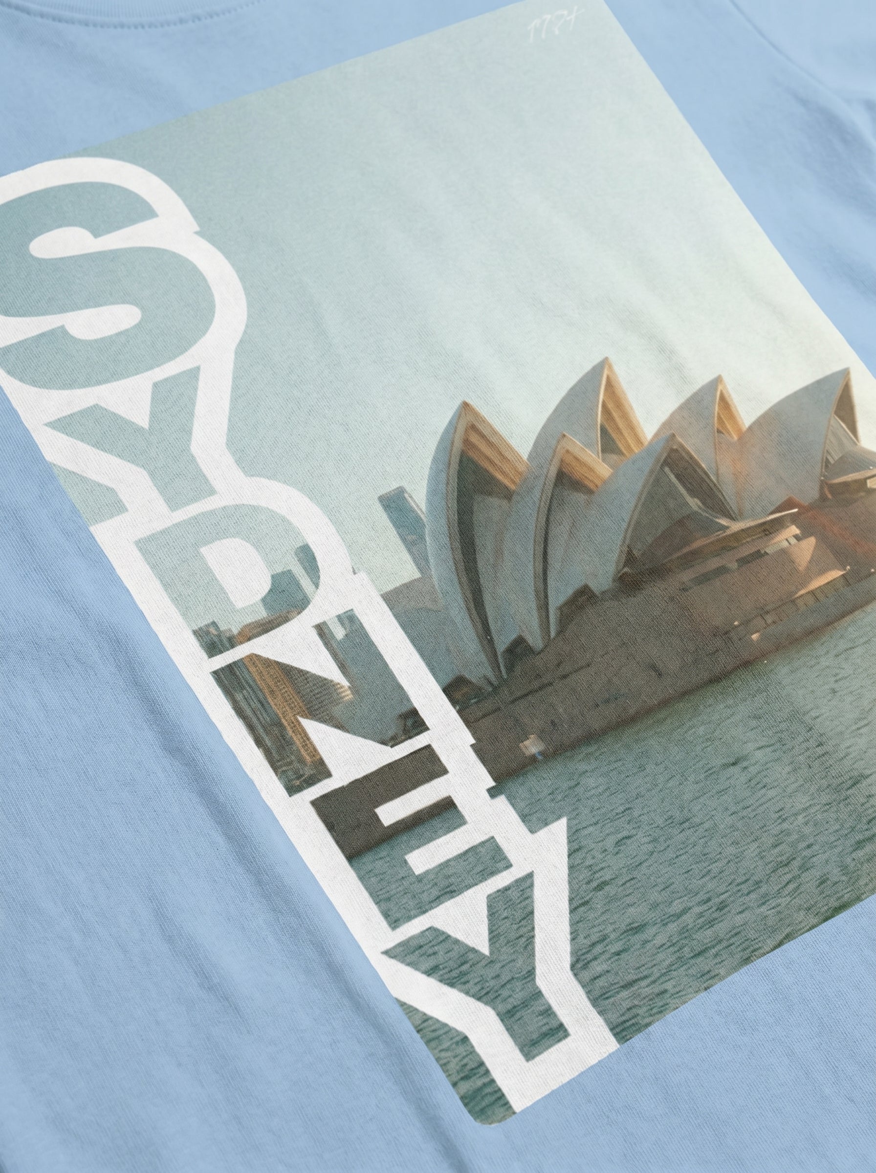T-shirt with Sydney Opera House design and 'Sydney' text on a light blue background
