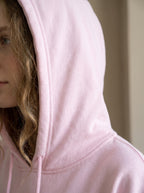 Person wearing a light pink hoodie with a neutral background